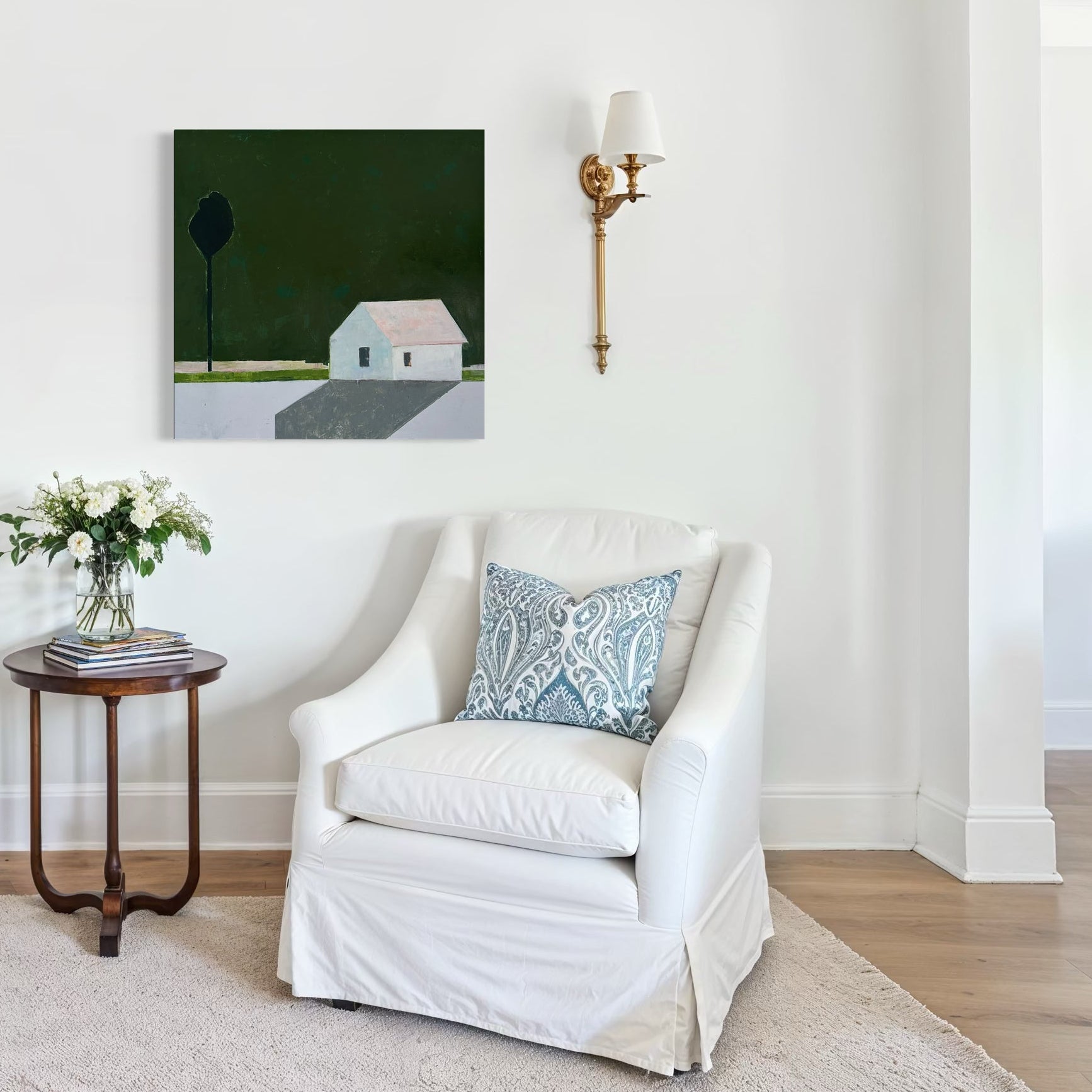 Living room with white armchairs, a small table with flowers, and a minimalist painting of a white house against a dark green background. 
