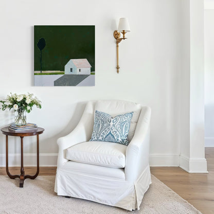 Living room with white armchairs, a small table with flowers, and a minimalist painting of a white house against a dark green background. 