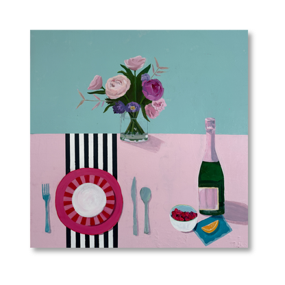 A pastel tabletop setting with a pink striped plate, utensils, a bottle of champagne, a bowl of raspberries, and a bouquet of flowers in a clear vase.