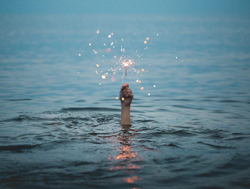 a hand holding a magic wand breaking through the surface of water