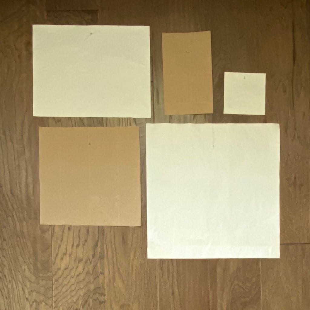 photo of multiple pieces of kraft paper cut to the size of artwork that will be used to hang gallery wall.