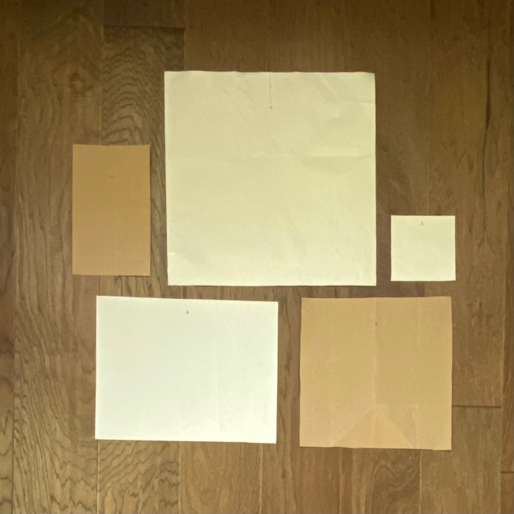 photo of multiple pieces of kraft paper cut to the size of artwork that will be used to hang gallery wall. these are arranged differently than previous image. 