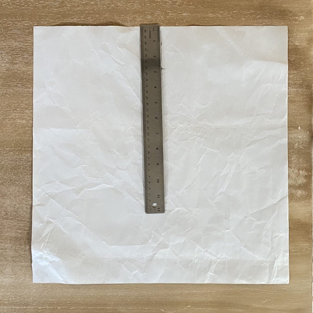 image of a piece of kraft paper with a ruler on top to mark where the nail should go to properly hang artwork
