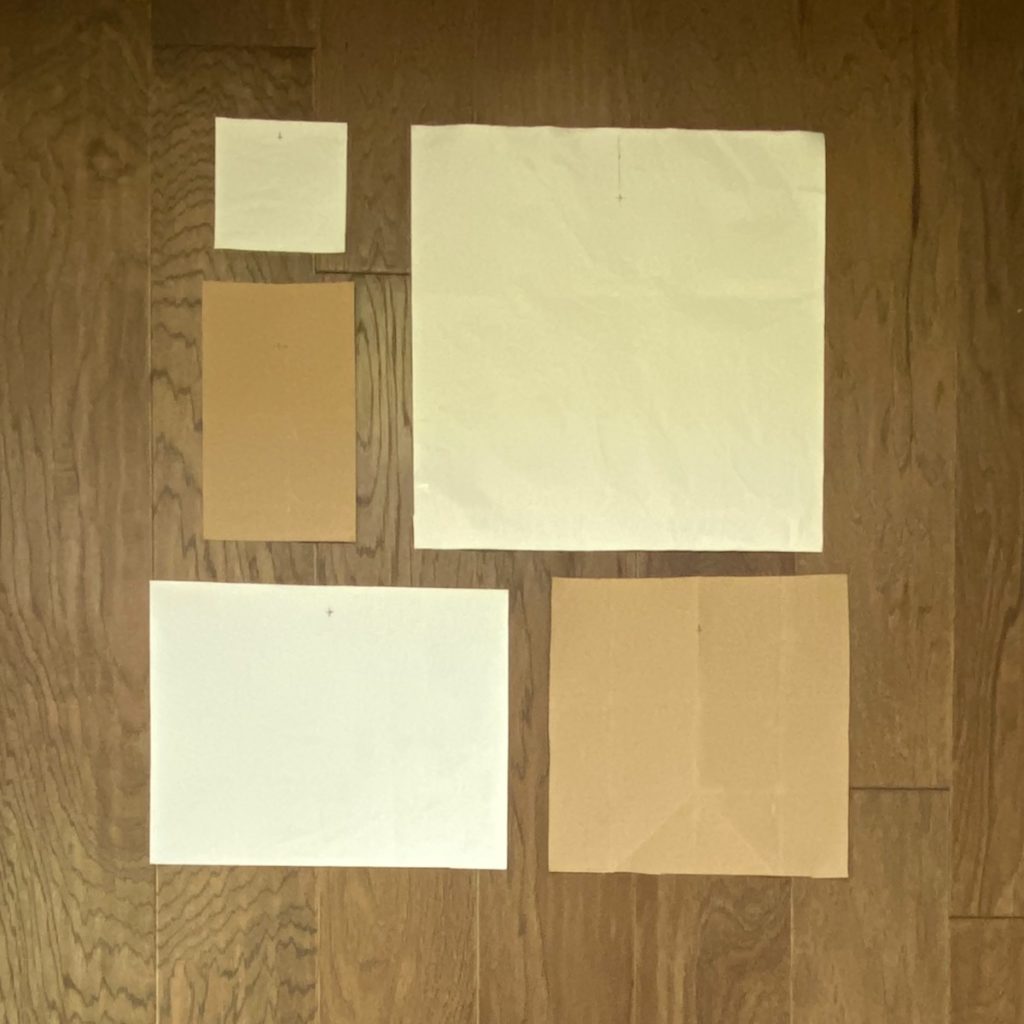 photo of multiple pieces of kraft paper cut to the size of artwork that will be used to hang gallery wall. these are arranged differently than previous image. 
